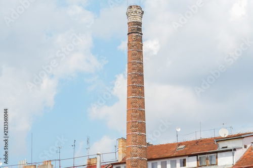 Fotografía Old brick chimney on a background of blue sky with white clouds