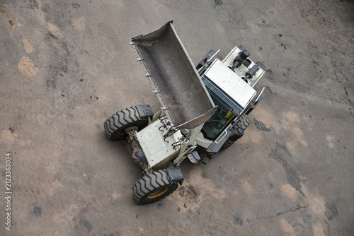 Aerial view of construction site where a front loader is loading soil, rocks, and debris into a dump truck, industrial work, excavation, and earthmoving processes