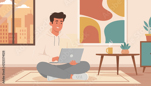 Young man sitting cross-legged on a cozy rug while working on his laptop computer inside a modern apartment.