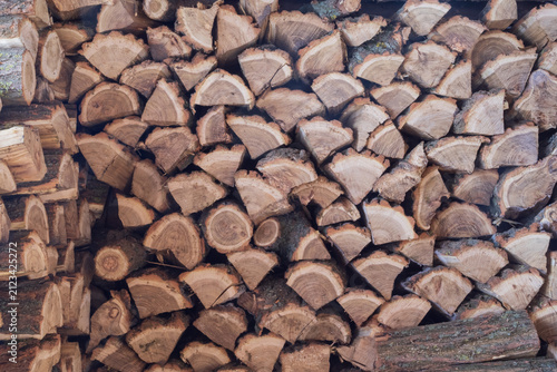 Pile of split firewood stacked for drying and winter heating. Natural wood texture, renewable fuel and rural household concept.
