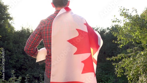 Fotografie Construction worker holds a white hard hat with a Canadian flag draped over his shoulder
