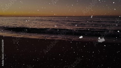 Snow falling over a calm sea at sunrise with gentle waves and golden morning light.