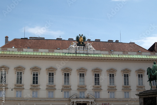 Dettaglio della facciata barocca del palazzo imperiale di Hofburg con finestre simmetriche e il monumentale stemma dell'aquila bicipite asburgica sul tetto in Josefsplatz a Vienna, Austria.