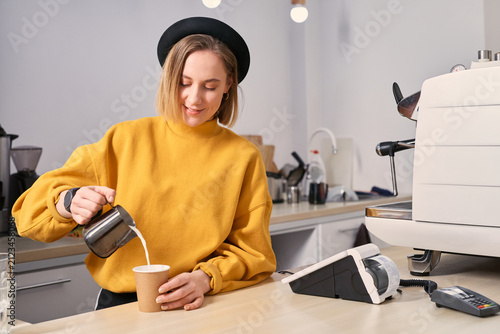 Barista pouring milk, making latte art, working at coffee shop