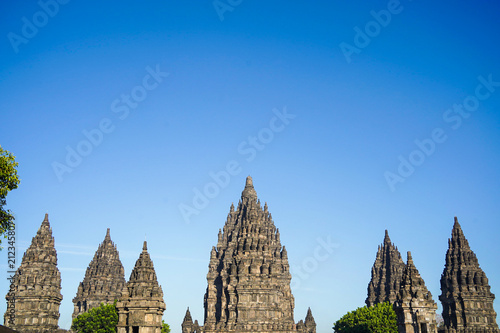 Konstfotografi Multiple Prambanan Temple spires form a dramatic stone skyline against a vivid cloudless blue sky near Yogyakarta, Indonesia