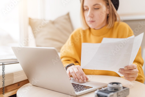 Woman working with papers and on a laptop, typing on keyboard, close up