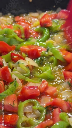Close-up of fresh colorful vegetables being sauteed in a hot pan, featuring diced potatoes, carrots, green peppers, and red chili peppers being stirred with a spatula. Perfect for cooking tutorials, h