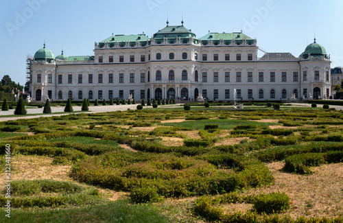 Facciata esterna del Palazzo del Belvedere Superiore con i monumentali giardini barocchi geometrici in primo piano sotto un cielo azzurro, famosa attrazione turistica e storica di Vienna, Austria.
