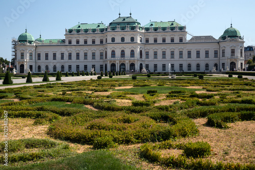Facciata esterna del Palazzo del Belvedere Superiore con i monumentali giardini barocchi geometrici in primo piano sotto un cielo azzurro, famosa attrazione turistica e storica di Vienna, Austria.