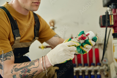 Quadro su tela Young adult Caucasian male plumber installing water valve during house renovation, representing home maintenance services
