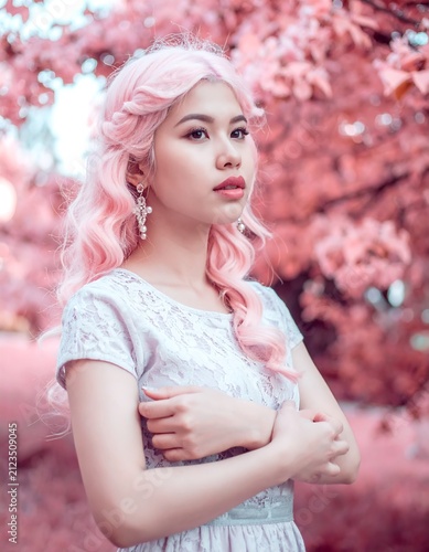 Young woman with pink hair in a garden with pink foliage