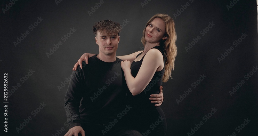 Obraz premium Young couple standing against a black background, showing connection and affection