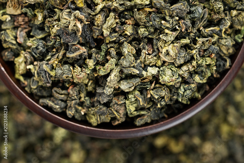 Premium Tieguanyin in dark wooden bowl on green tea pattern background