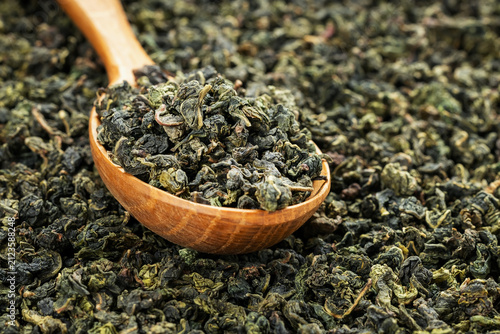 Green oolong tea scoop on flat background wooden spoon macro