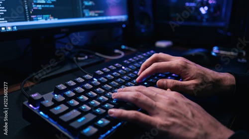 Obraz w ramie Professional programmer typing code on backlit mechanical keyboard, software development, dark room with monitor displaying programming language syntax for web application building