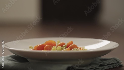 Slow motion making pesto penne pasta with mozzarella and tomatoes in deep plate closeup