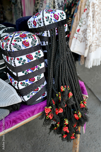 Bild auf Leinwand Traditional Uzbek women's embroidered skullcaps with decorative artificial braids displayed for sale at a local handicraft market