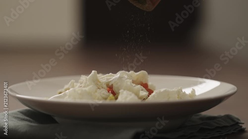 Slow motion making pesto penne pasta with mozzarella and tomatoes in deep plate closeup