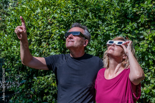A couple of adults wears protective glasses to observe the sun and its upcoming eclipse