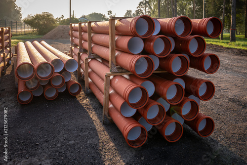Konstfotografi Stacked Orange Drainage Pipes Await Installation in Outdoor Construction Yard