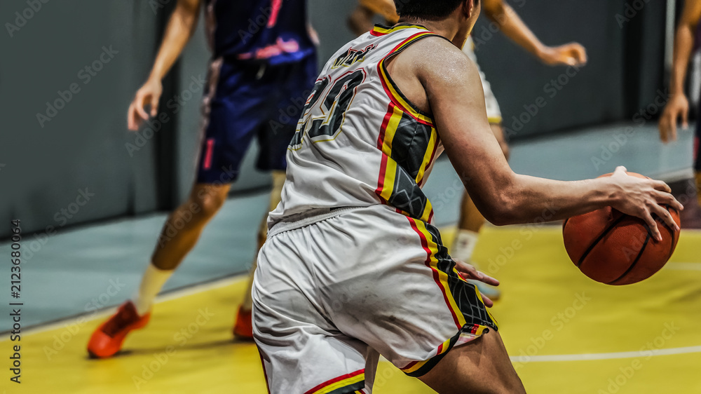 Fototapeta premium Basketball player dribbling the ball during an indoor competitive game