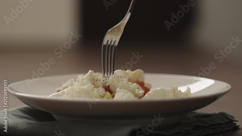 Slow motion making pesto penne pasta with mozzarella and tomatoes in deep plate closeup