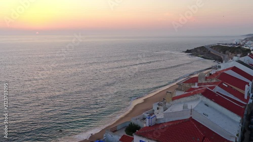 Flyover the old town of Ericeira and Praia do Norte in Portugal at sunset.