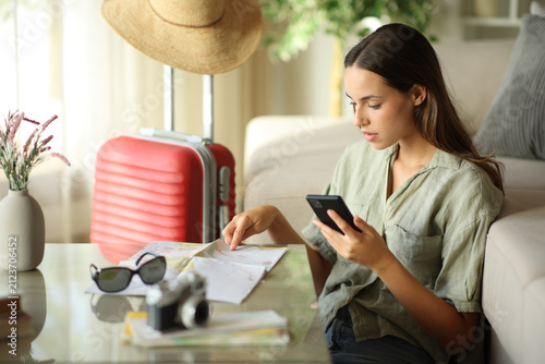 Tourist checking paper guide and phone on vacation