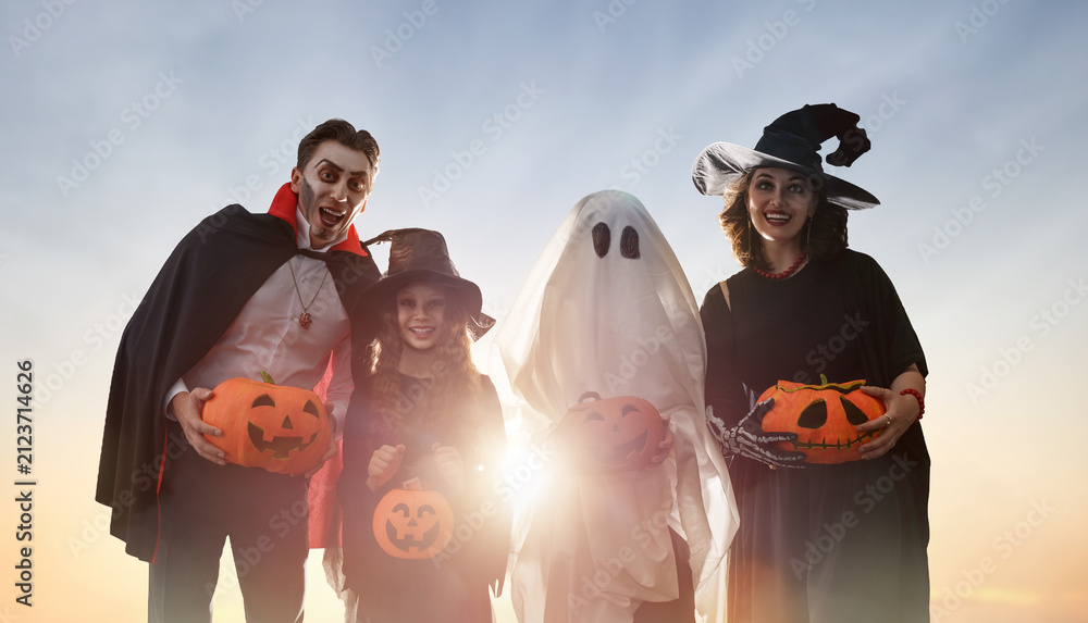 Obraz premium Happy Family in Halloween Costumes Celebrating Outdoors at Sunset