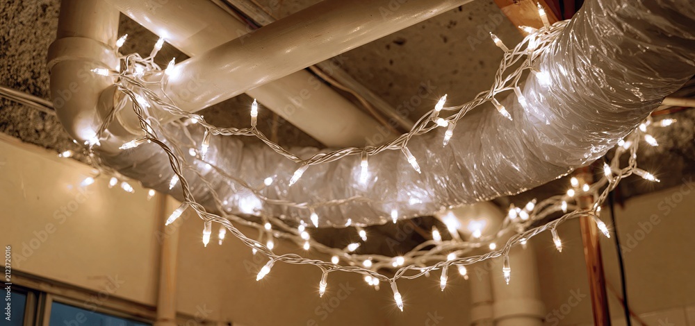 Obraz premium In a cozy basement, exposed pipes adorned with twinkling fairy lights add festive warmth and charm.