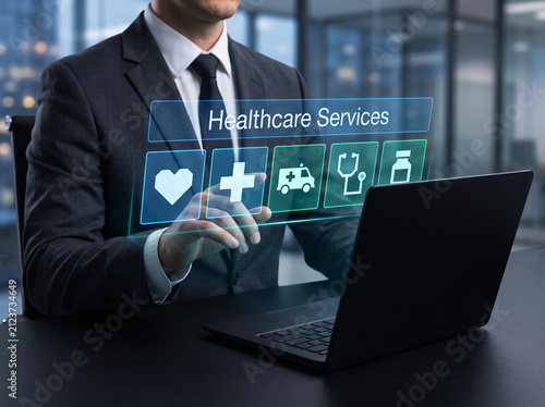 Doctor or medical administrator engaging with interactive digital healthcare services panel showing vital care icons and hospital network management.