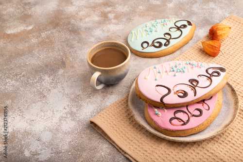 Glazed pink and blue decorated cookies on brown concrete, copy space, side view