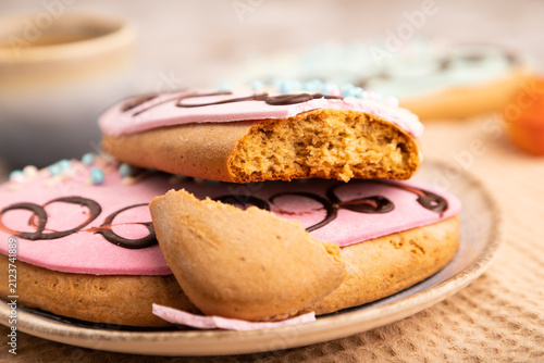 Glazed pink and blue decorated cookies on brown concrete, close up, side view, selective focus