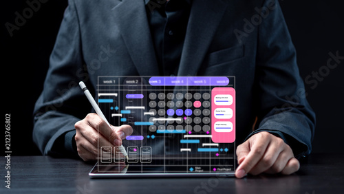 Project management Gantt chart and schedule planning software concept. Businessman using stylus pen on tablet with virtual timeline calendar, meeting tasks and audit documents on dark background.