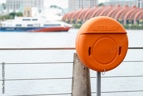 lifebuoy by river for rescue in emergency on cloudy day, floating rescue tool thrown to a person in the water to stop them from sinking, shallow depth of field, copy space