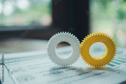 Sustainable operations and green technology synergy concept, interlocking gears on environmental ESG net zero document.