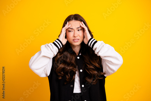 Quadro su tela Young woman with headache holding temples in frustration on yellow background, p
