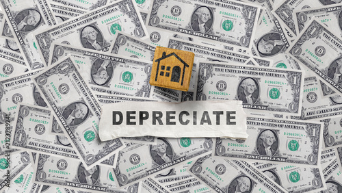 фотографія A wooden block with a house icon and a paper with the word DEPRECIATE lie on US dollar bills, representing real estate value loss