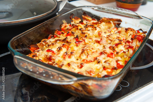 A Baked Vegetable Casserole of Cauliflower made with Potato, Sweet Bell Red Pepper, Chicken, Cheese and Tomatoes in Glass Baking Dish. Selective Focus.