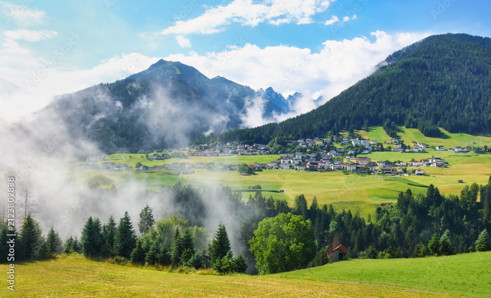 Obraz premium Village in green Austria Alps valley with big mountain in background near Kuthai