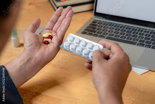 Foto A male office worker taking painkiller medication while sitting at his desk in a modern office environment