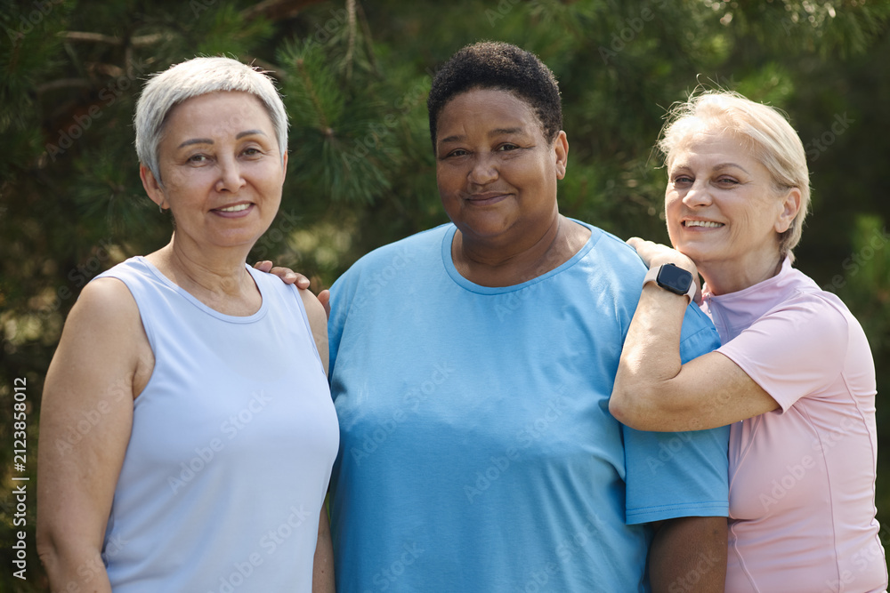 Fototapeta premium Portrait of diverse group of senior women smiling together in park, representing active aging and social inclusion. Image suitable for healthcare and wellness marketing campaigns