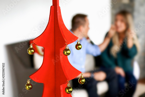 Red Wooden Christmas Tree with blurred Couple Talking in Background
