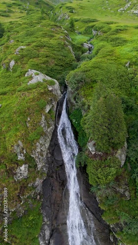 Vertical drone flight over mountain waterfall and dramatic landscape at sunset