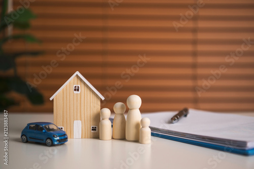 Foto Family insurance planning with wooden house car and figurines beside policy documents representing financial protection asset coverage security and future stability
