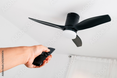 man operating a ceiling fan with remote control