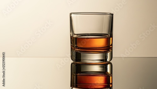 Amber spirit in a clear glass, reflecting on a polished surface