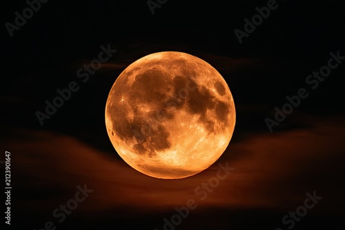 A large, orange celestial body dominates the dark sky, partially obscured by wispy clouds
