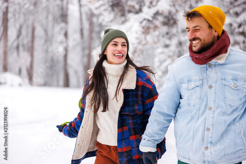 Fotografie Couple having fun going sliding in the snow in the mountains while on winter vac