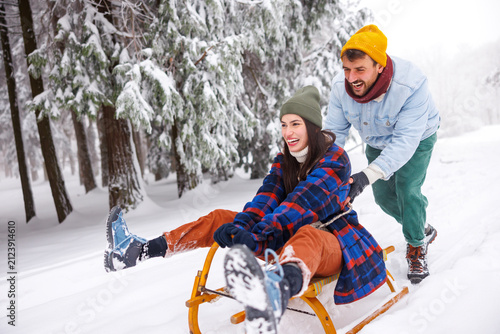 Принти на полотні Man pushing woman on sledge while on winter vacation